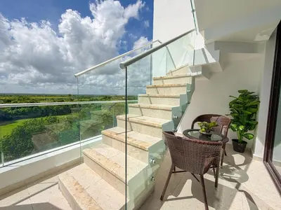 a glass staircase with a table and chairs on a balcony at Cana Rock Penthouse Golf Views & Infinity Pool in Punta Cana