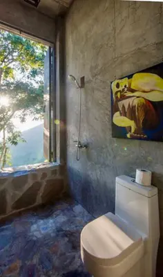 a bathroom with a toilet with a window and a painting at House Cottage in Caribbean Mountains 2