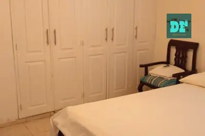a bedroom with a bed and a chair and cabinets at Villa Eli in Puerto Plata
