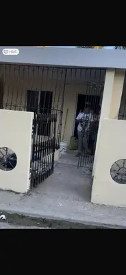 a building with a gate and a person standing outside at santo domingo airport villa in Reparto Esther Rosario