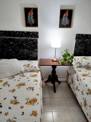 a bedroom with two beds and a desk with a table at Hotel El Almendro in Pedernales