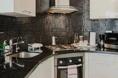 a kitchen with a stove top oven next to a sink at Chic Elegant City Center Condo in Santo Domingo