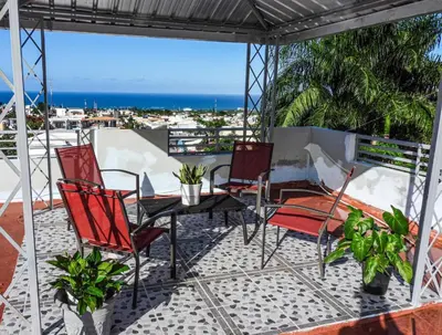a patio with chairs and a table with a view of the ocean at Majestic View Apartment II in San Felipe de Puerto Plata