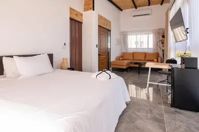 a bedroom with a white bed and a couch at Casa Ola & Surf in San Felipe de Puerto Plata
