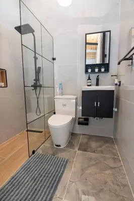 a bathroom with a toilet and a glass shower at Casa Ola & Surf in San Felipe de Puerto Plata