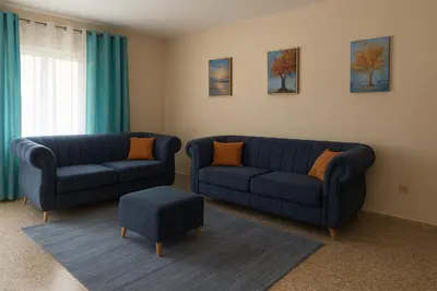 a living room with two blue couches and a stool at Bright & Spacious En-suite Room - Santo Domingo Este in Cancino