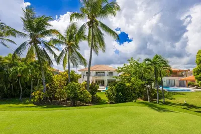 a house with palm trees in front of a yard at Buganvilla 252 Cocotal Villa - 4BR, Private Pool, Jacuzzi, Golf View in Punta Cana