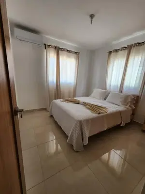a bedroom with a bed with white sheets and windows at Cerro hermoso in Santiago de los Caballeros