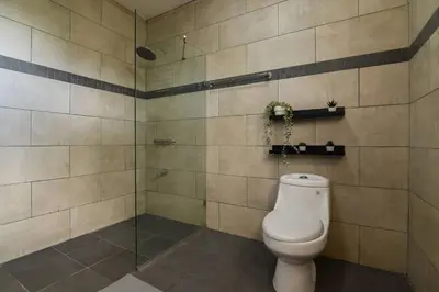 a bathroom with a toilet and a glass shower at Casa Mango- Relax - Pool Stunning Views in San Felipe de Puerto Plata