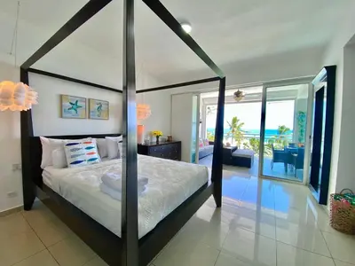 a bedroom with a canopy bed with a view of the ocean at Cozy Beach Front Condo, Pool in La Puntica de Juan Dolio