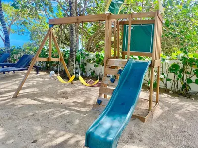 a playground with a blue slide and a swing at Cozy Beach Front Condo, Pool in La Puntica de Juan Dolio