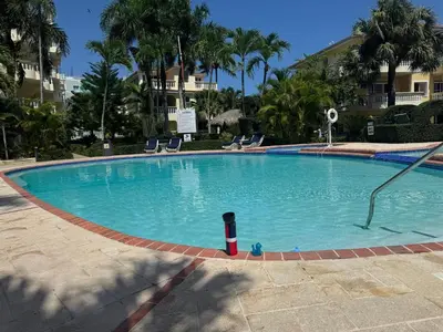 a large swimming pool with chairs in a resort at Marvilla - Coastal Condo Poolside & Ocean View in Boca Chica