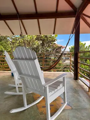 a white rocking chair hanging from a porch at Clave Verde Ecolodge in Las Terrenas