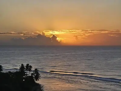 a sunset over the ocean with palm trees on the beach at Apartamento Hermoso Frente Al Mar 11fl Amanzing in Juan Dolio