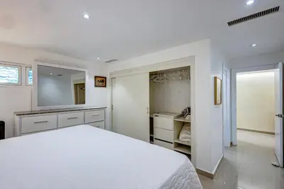 a white bedroom with a bed and a mirror at Apartamento Hermoso Frente Al Mar 11fl Amanzing in Juan Dolio