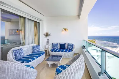 a living room with chairs and a balcony with the ocean at Apartamento Hermoso Frente Al Mar 11fl Amanzing in Juan Dolio