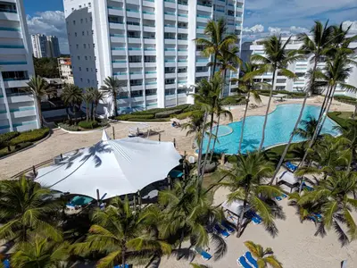 an aerial view of a resort with a pool and palm trees at Apartamento Hermoso Frente Al Mar 11fl Amanzing in Juan Dolio