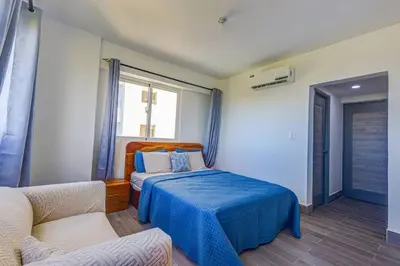 a bedroom with a bed and a couch and a window at Coralclifftower in Juan Dolio