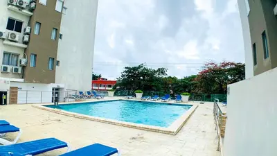 a swimming pool with blue lounge chairs and a building at Apartamento en Boca Chica T2 707 in Boca Chica