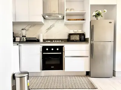 a kitchen with white cabinets and a stainless steel refrigerator at Comfy Apt, Rooftop Lounge, Pool in Santo Domingo