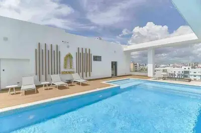 a swimming pool with chairs and a building at Comfy Apt, Rooftop Lounge, Pool in Santo Domingo