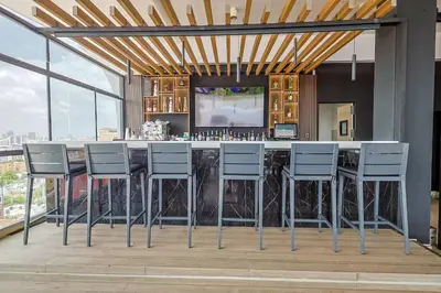 a kitchen with a bar with stools and a television at Comfy Apt, Rooftop Lounge, Pool in Santo Domingo