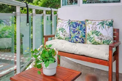 a bench on a porch with pillows and a table at Comfy 1BR Apt, Centric Full AC in Santo Domingo