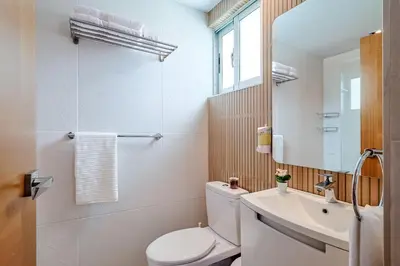 a bathroom with a toilet and a sink and a mirror at Comfy 1BR Apt, Centric Full AC in Santo Domingo
