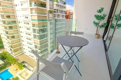 a table and chairs on a balcony with buildings at Luxury Upscale Centric Condo, in Santo Domingo