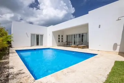 a swimming pool in front of a white house at Sosua Ocean Village Villa 24 in Sosúa