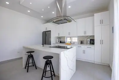 a kitchen with white cabinets and a counter with stools at Sosua Ocean Village Villa 24 in Sosúa