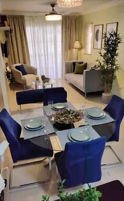 a living room with a table and blue chairs at green oasis vacation retreat in La Grúa