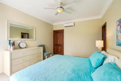 a bedroom with a blue bed and a dresser at Stylish Punta Cana Apartment - Eden Caribe in Punta Cana