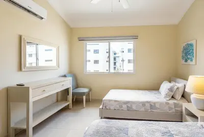 a bedroom with a bed and a desk and window at Stylish Punta Cana Apartment - Eden Caribe in Punta Cana