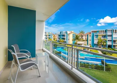 a balcony with two chairs and a view of the pool at Stylish Punta Cana Apartment - Eden Caribe in Punta Cana