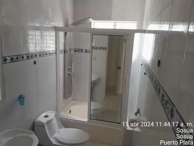 a white bathroom with a shower and a toilet at 4 bedroom villa, private pool, ocean view, security in Sosúa