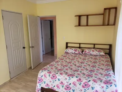 a bedroom with a bed with a floral bedspread and pillows at 4 bedroom villa, private pool, ocean view, security in Sosúa