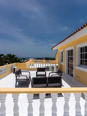 a patio with black furniture on a yellow house at 3BR Villa Newly Renovated-5 min to Playa Dorada H1 in Puerto Plata