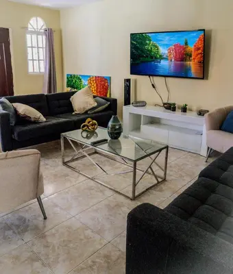 a living room with a couch and a tv on the wall at 3BR Villa Newly Renovated-5 min to Playa Dorada H1 in Puerto Plata