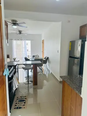 a kitchen with a table and a stainless steel refrigerator at Apartamento muy cerca de la embajada Americana in Santo Domingo