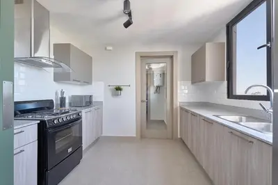 a white kitchen with a sink and a stove at ®{PANO~VIEW~Experience} @DowntownSD PoolGym2BR in Santo Domingo