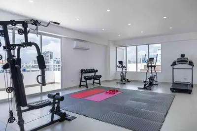 a gym with exercise equipment in a room with windows at ®{LUX~City~Skyline} @DowntownSD PrivéJaccuziGym in Santo Domingo
