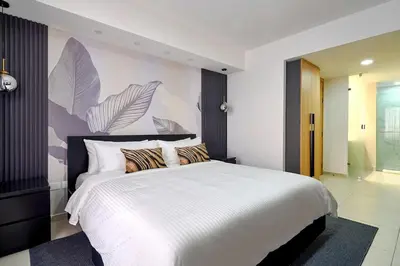 a bedroom with a large white bed with a painting on the wall at ®2BR{The~City~Center}@DTown PoolGym NearCecilip in Santo Domingo