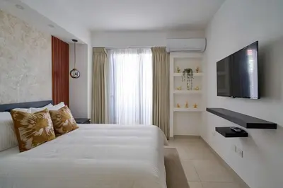 a bedroom with a white bed and a flat screen tv at ®2BR{The~City~Center}@DTown PoolGym NearCecilip in Santo Domingo