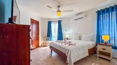 a bedroom with a large bed with blue curtains at Renaissance Residence Cabarete in Cabarete