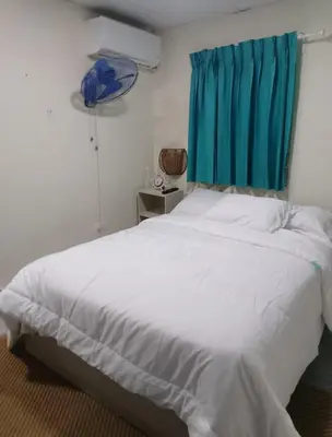 a bedroom with a large white bed with a blue curtain at Habitacion cerca de la Playa in Boca Chica
