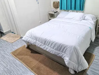 a bedroom with a white bed with a blue curtain at Habitacion cerca de la Playa in Boca Chica