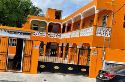 an orange building with a car parked in front of it at Apartamentos España in Sosúa