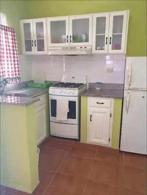 a kitchen with white cabinets and a white stove at Apartamentos España in Sosúa