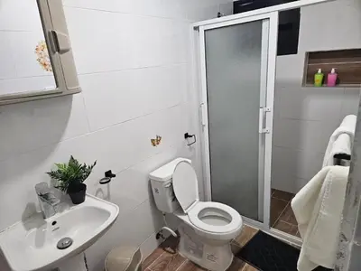 a bathroom with a shower and a toilet and a sink at Eastern Breeze in Hainamosa